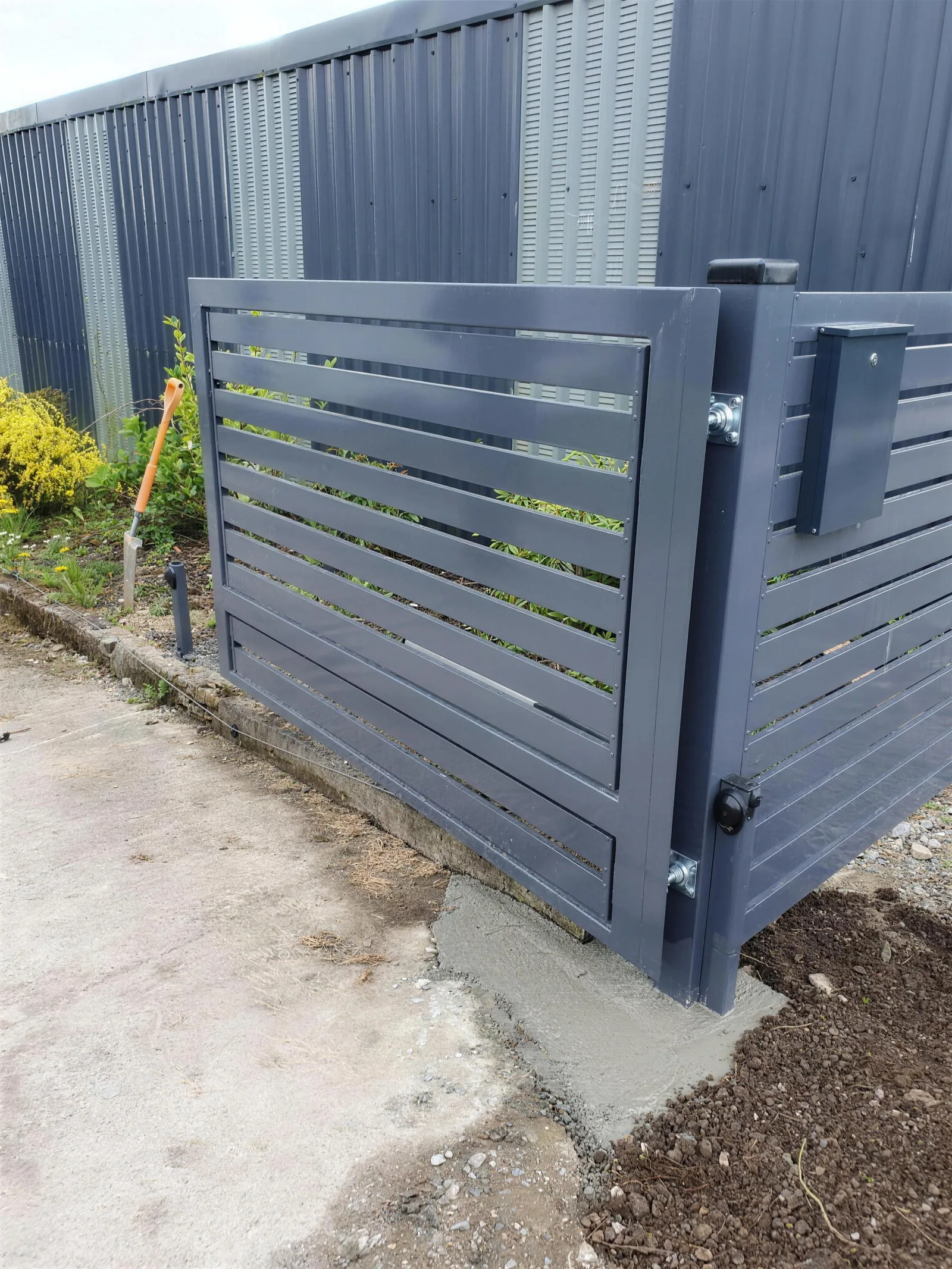 Anthracite horizontal slat side gate with a post box on the pillar